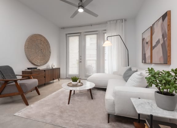 a living room with white furniture and a ceiling fan
