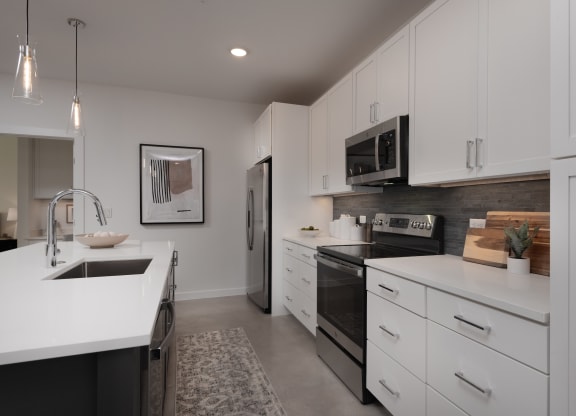 an open kitchen with white cabinets and black appliances and a sink