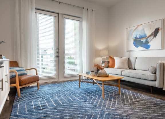 a living room with large windows and a blue rug