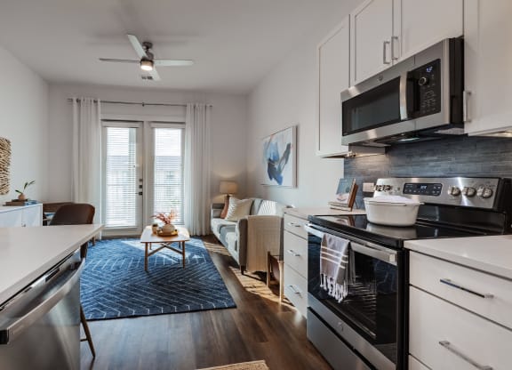 a kitchen and living room with a stove and a microwave