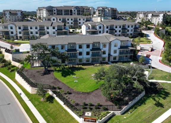 an aerial view of an apartment complex with a green lawn and a road