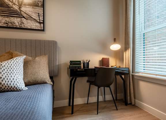 A room with a bed, desk, and chair.