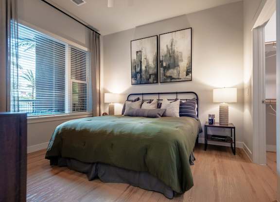 A bedroom with a bed, nightstand, and two framed pictures on the wall.