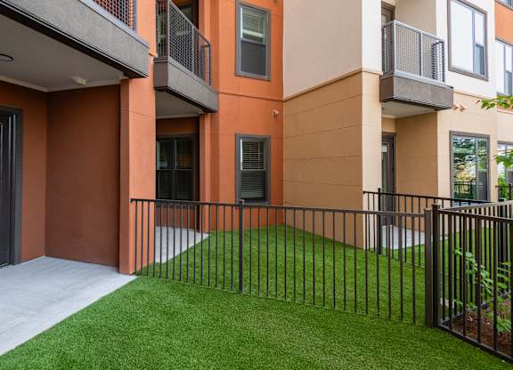 A modern building with a black fence and green grass in front.