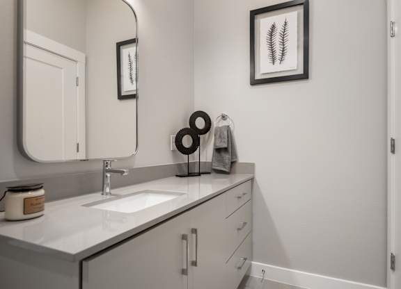 A bathroom with a sink, mirror, and a framed picture on the wall.