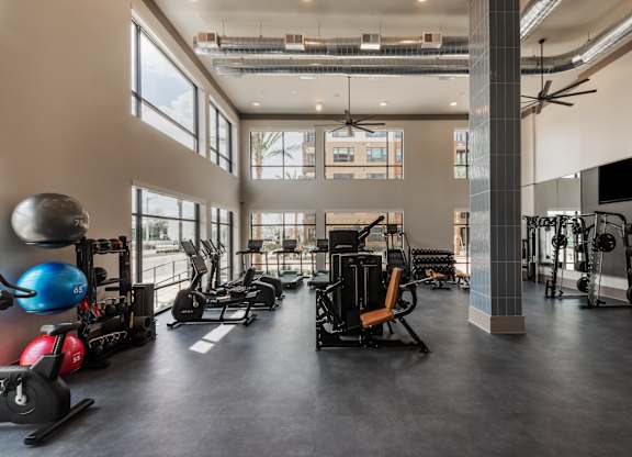 A spacious gym with various exercise equipment and a large window.