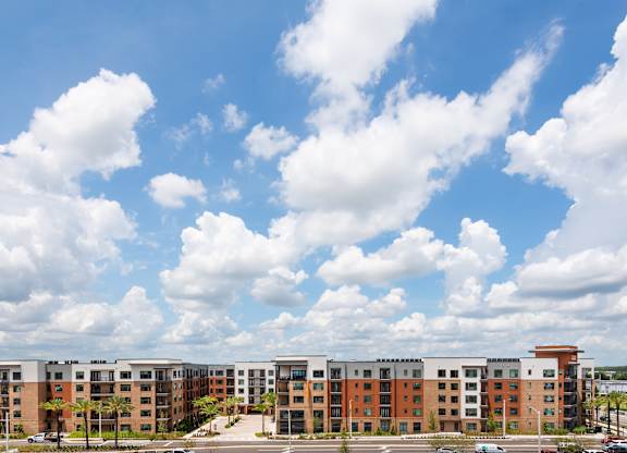 A large apartment complex with a parking lot in front.