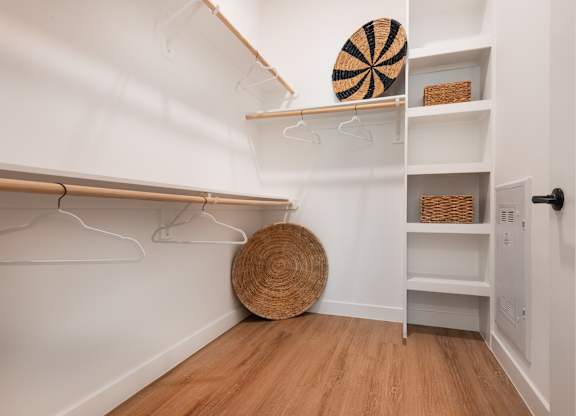 A white closet with a basket and a round straw hat on the floor.