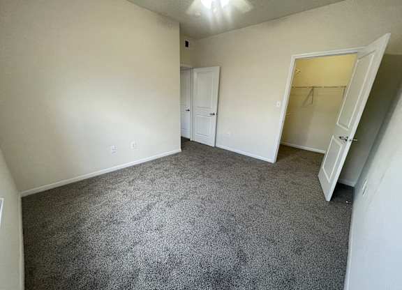 A room with carpeted floor and two doors.