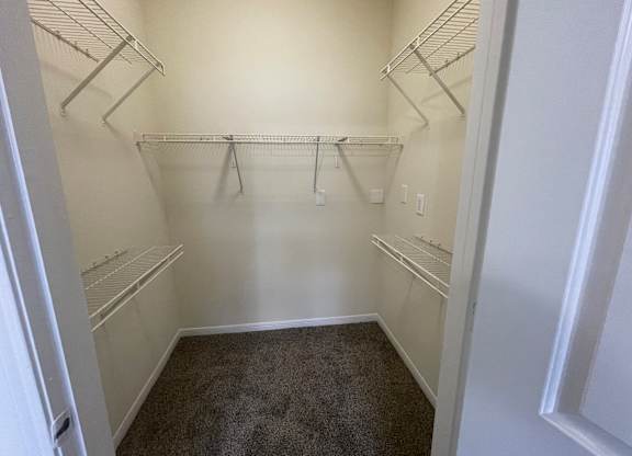A walk-in closet with white walls and shelving.