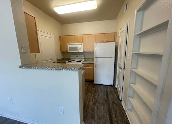 A kitchen with a white refrigerator and a microwave above the counter.