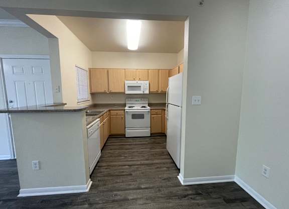 A kitchen with white appliances and wooden cabinets.