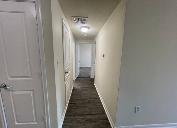 A long hallway with a door on the left and a light on the right.