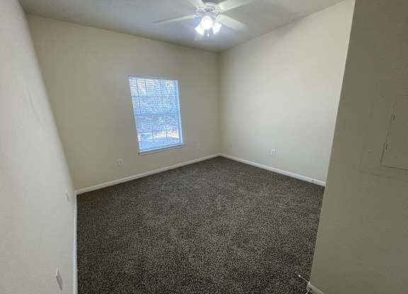 A room with a ceiling fan and a window showing a snowy scene outside.