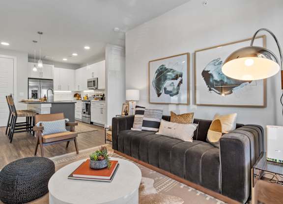 A modern living room with a grey couch, a white coffee table, and a large lamp.