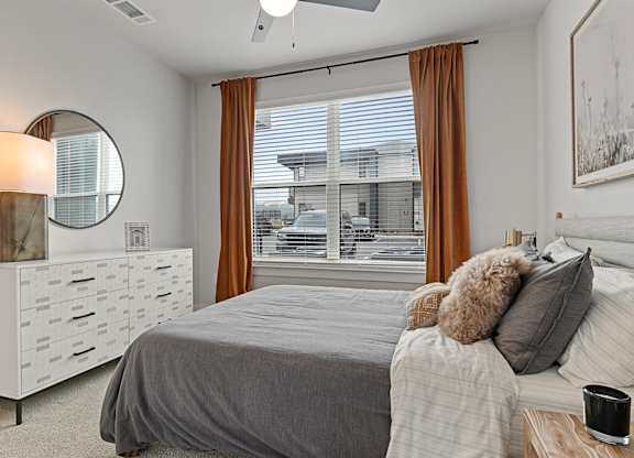 A bedroom with a bed, nightstand, and window with curtains.