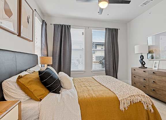 A bedroom with a bed, nightstand, and a window with blinds.