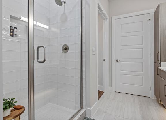 A white door is in a bathroom with a glass shower door.
