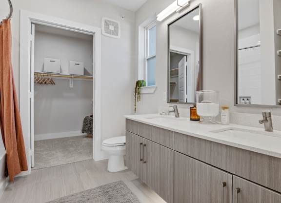 A bathroom with a toilet, sink, and mirror.