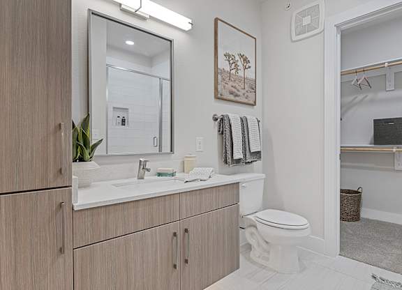 A bathroom with a toilet, sink, and mirror.