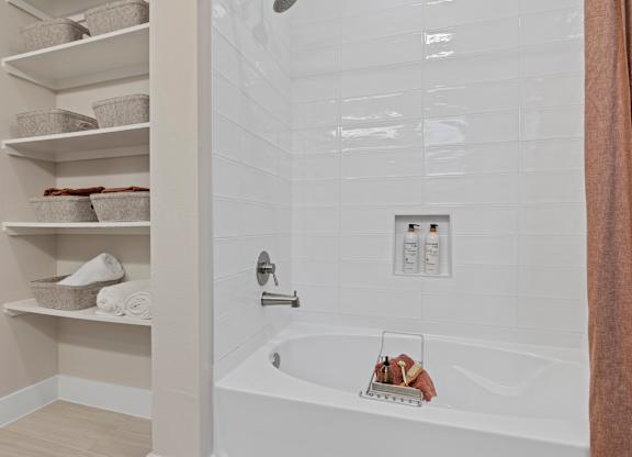 A white bathtub with a towel rack and towels on the shelves.