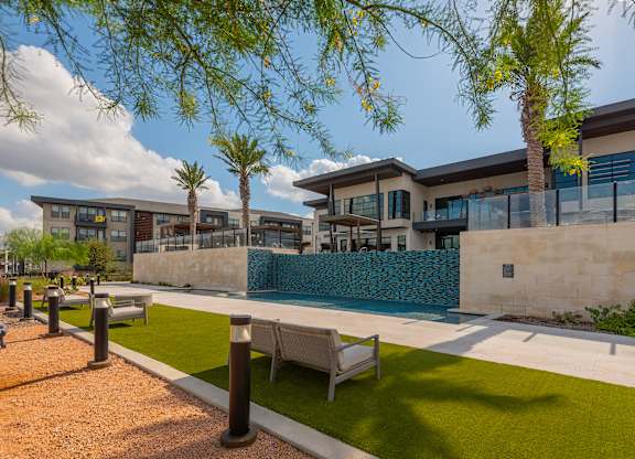 A modern building with a pool and palm trees.