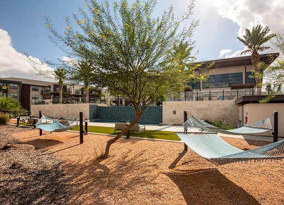 A playground with a slide and a tree in the foreground.