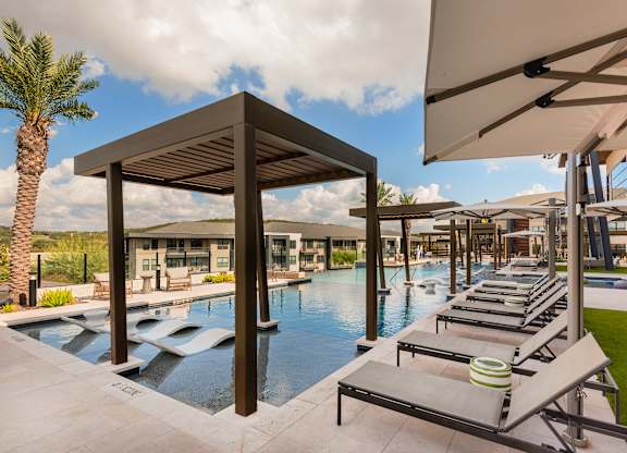 A pool area with sun loungers and a wooden pavilion.