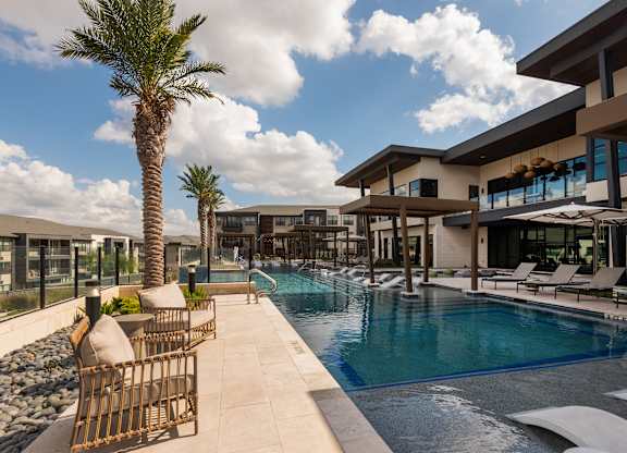 A pool area with a palm tree and a building in the background.