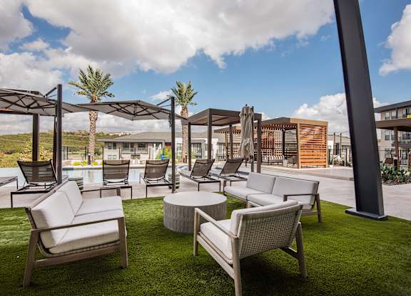 A patio with white furniture and a pool.