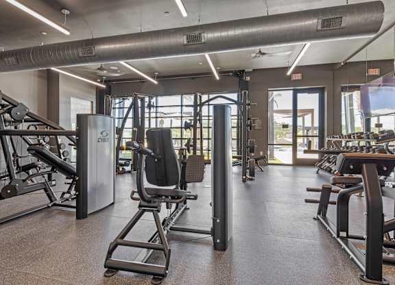 A gym with a variety of equipment including a squat rack, a leg press machine, and a bench press.