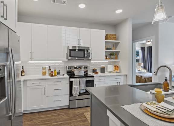 A modern kitchen with white cabinets and stainless steel appliances.