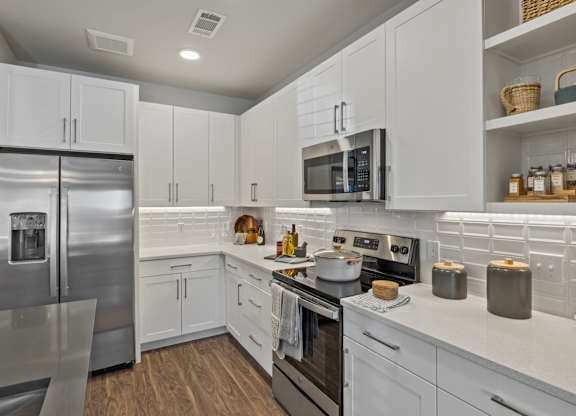 A modern kitchen with white cabinets and stainless steel appliances.
