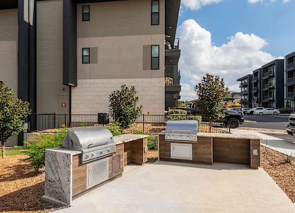A modern outdoor kitchen area with a grill and sink.
