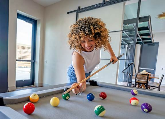 A woman with curly hair is playing pool.