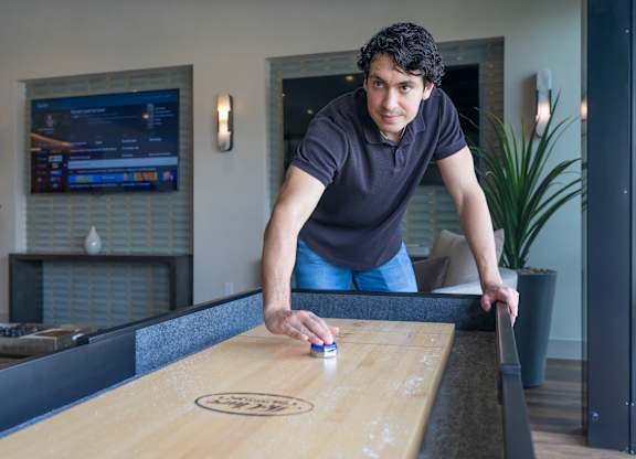 A man is playing shuffleboard in a room.