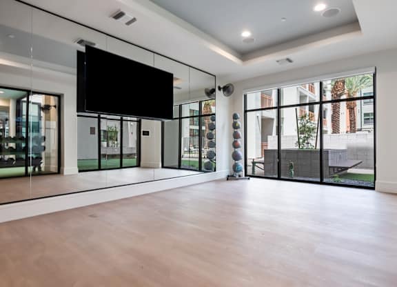 A spacious room with a television mounted on the wall and sliding glass doors.