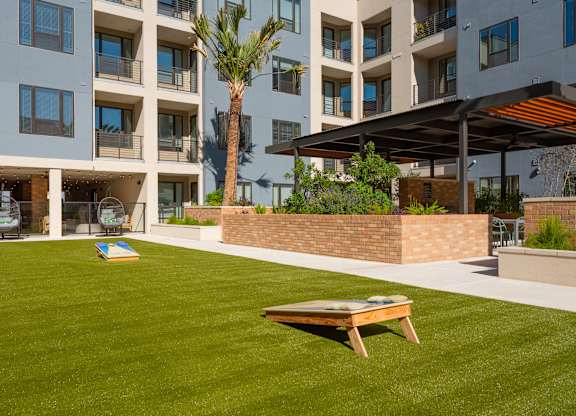 a lawn with a picnic table in front of an apartment building