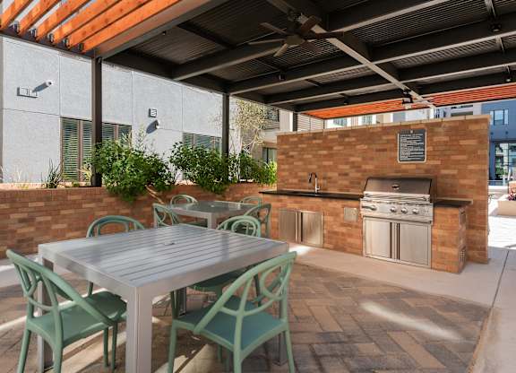 a patio with a table and chairs and an outdoor kitchen