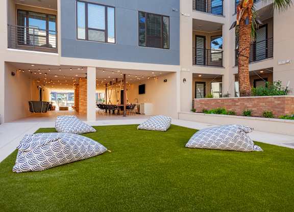 four pillows on a lawn in front of an apartment building