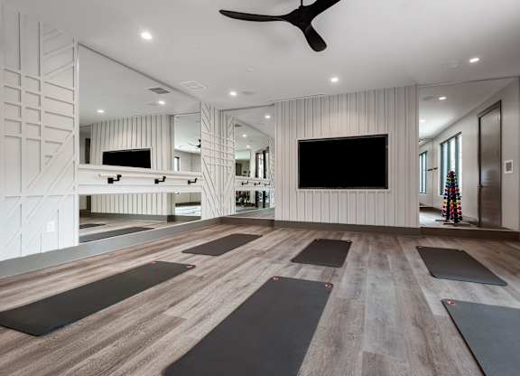 a spacious yoga room with a large flat screen tv on the wall and a row of yoga