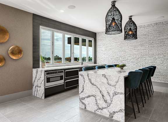 a kitchen with white marble countertops and a long island with blue chairs