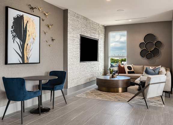 a living room with a couch table and chairs and a flat screen tv on the wall