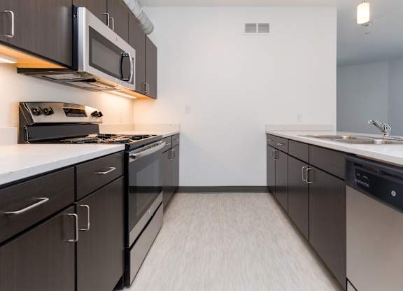 Modern open-concept kitchen and living area with stainless steel appliances.
