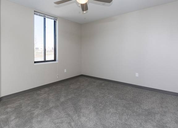 Bright, vacant bedroom with neutral walls and carpet flooring.