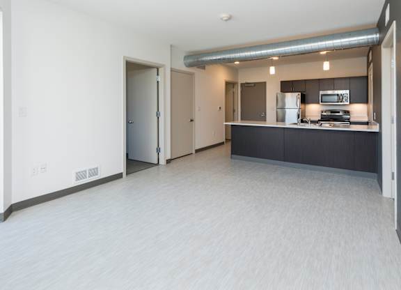 Modern open-concept kitchen and living area with stainless steel appliances.
