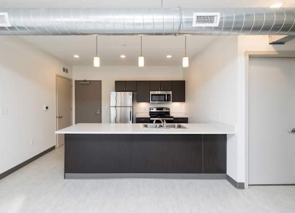 Modern open-concept kitchen and living area with stainless steel appliances.