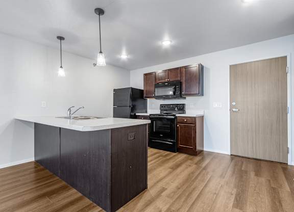 A kitchen with a white counter top and wooden floors.
