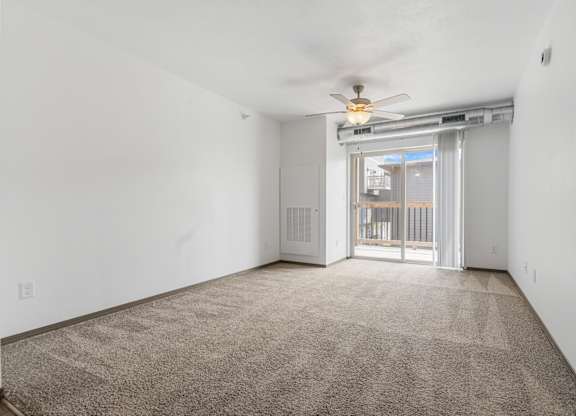 A room with a carpet floor and a ceiling fan.