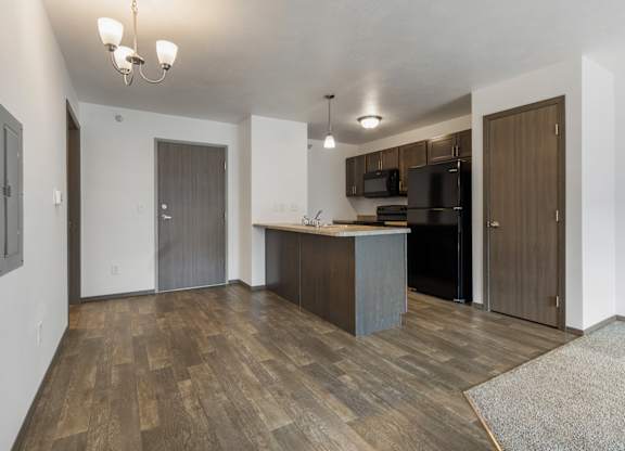 A kitchen area with a wooden floor and a bar area.